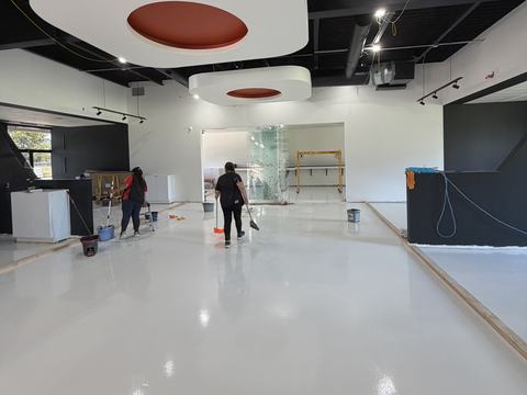 Cleanstate crew cleaning a new glossy epoxy floor in a commercial space during a post-construction final clean in Houston