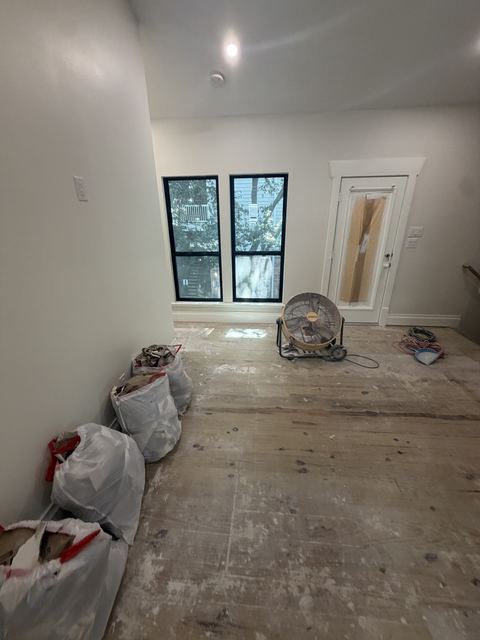 Construction debris bags and dusty subfloor in a Houston home before a rough clean